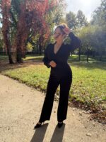 Czarny kombinezon Virelle na modelce — cała sylwetka, ujęcie z uniesioną ręką